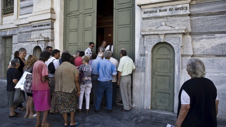 يونانيون ينتظرون الدخول إلى أحد فروع البنك الوطني في أثينا بتاريخ 20 يوليو/تموز