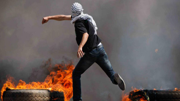 فلسطيني يرشق حجرا على جنود الاحتلال